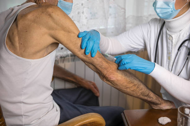 istock Senior man getting vaccinated by visiting nurse at home 1291371605