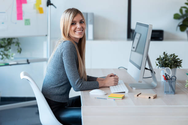 istock Beautiful young business woman working with computer while smiling looking at camera in the office. 1291372734