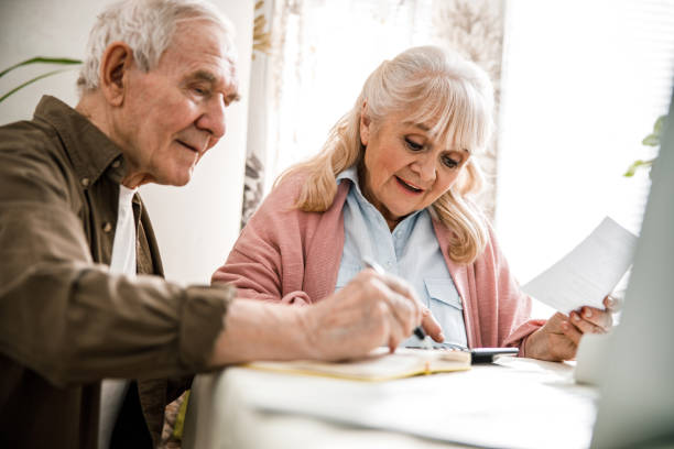 istock Elderly couple counting on calculator together 1291374281