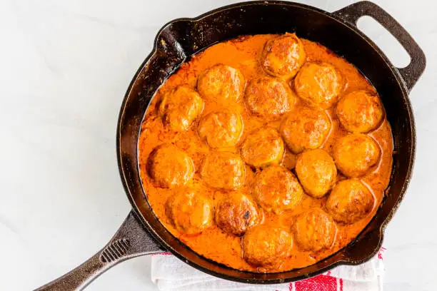 Butter Chicken Meatballs in a Skillet Directly Above on White Background, Indian Food Photography