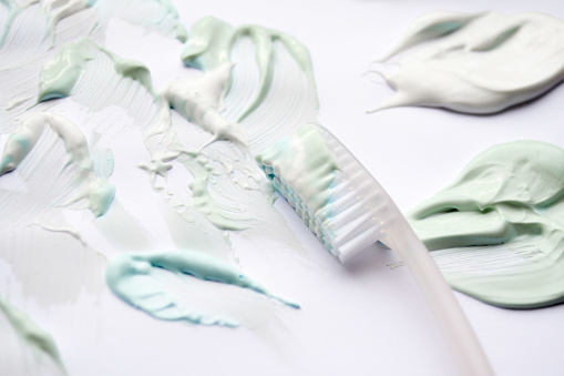 White toothbrush and toothpastes in three colors: green sweet mint, blue strong mint and white-whitening. White background, copy space. The concept of oral hygiene.