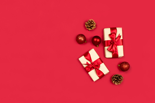 Gifts, fir cones, red decorations flat lay on red background top view, copy space. Creative christmas composition. Christmas shopping. Happy new year, xmas celebration concept. Stock photo