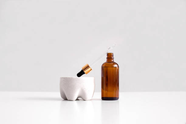 Serum, oil, acid, lotion in opened brown dropper glass with pippete on concrete pedestal side view with copy space. Spa products. Organic, natural cosmetic. Beauty, skincare concept. Stock photo suero, aceite, ácido, loción en vidrio gotero marrón abierto con pippete sobre la vista lateral del pedestal de hormigón con espacio de copia. productos de spa. orgánico, cosmético natural. belleza, concepto de cuidado de la piel. foto de stock