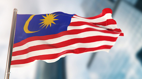 National Flag of Malaysia Against Defocused City Buildings