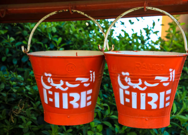 우물 에 매달려 두 개의 빨간 화재 양동이. 영어와 아랍어 스크립트 - fire bucket 뉴스 사진 이미지