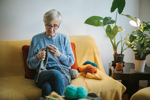 Woman in retirement knitting a swatter in her living room