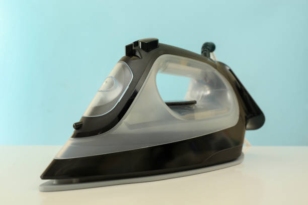 istock Iron on white table against blue background, close up 1291391041