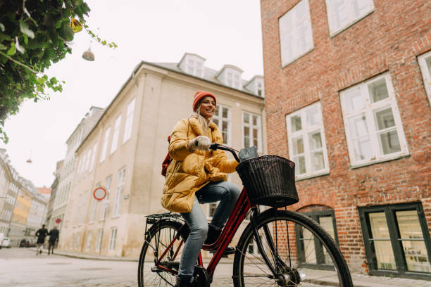 Bike ride in my city Photo of a smiling young woman riding a bike around the city, on a cold winter morning. winter city stock pictures, royalty-free photos & images