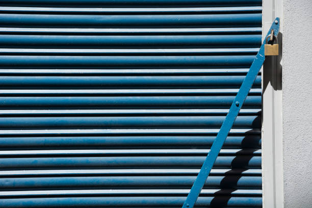 Abstract with blue metal shutter and vertical bar with padlock and its shadow to close a warehouse. Concept. Security. Business