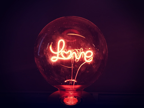 a warm gold light lamp with neon script word love glowing in the dark, home design decore