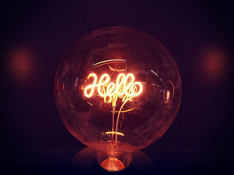 a warm gold light lamp with neon script word hello glowing in the dark, home design decore