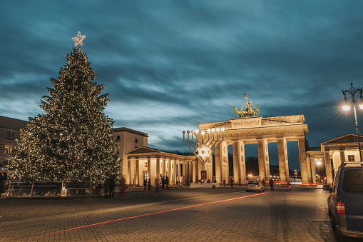 illuminated menorah symbol and christmas tree in front of Brandenburg gate in Berlin at blue hour at december evening 2020