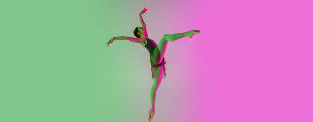 istock Young and graceful ballet dancer isolated on gradient pink-green studio background in neon light. Art in motion 1291412833