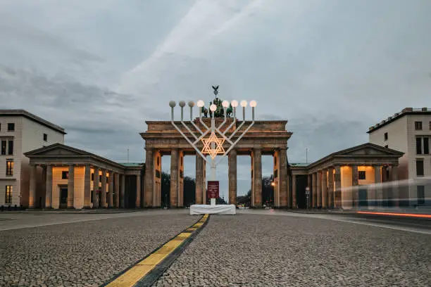 Photo of illuminated menorah symbol in front of Brandenburg gate in Berlin