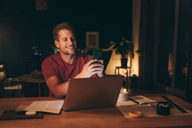 istock Handsome Young Businessman Using a Mobile Phone while Working on a Laptop 1291413568