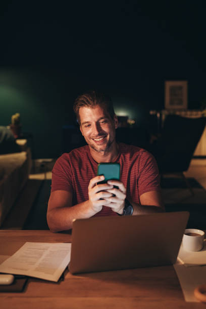istock Handsome Young Businessman Using a Mobile Phone while Working on a Laptop 1291413578