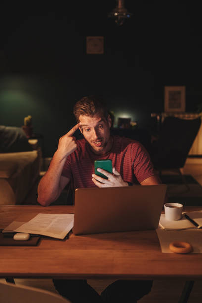 istock Handsome Young Businessman Using a Mobile Phone while Working on a Laptop 1291413581