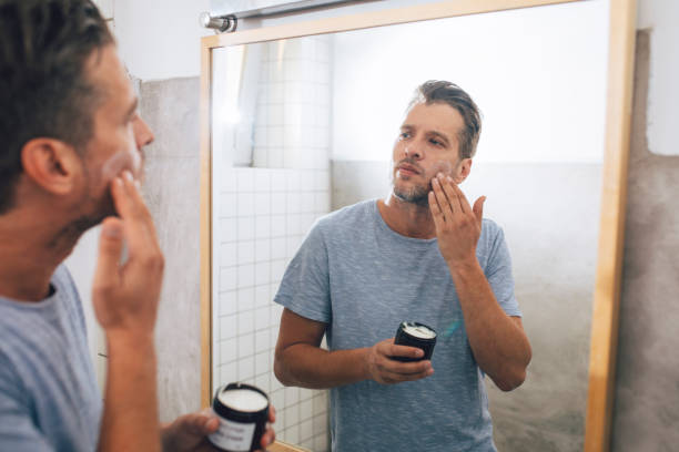 istock Handsome Young Man Applying an Aftershave Moisurizer after a Morning Shave 1291413590