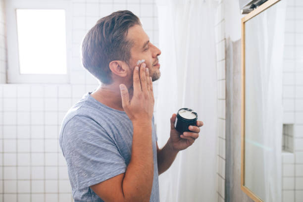 istock Handsome Young Man Applying an Aftershave Moisurizer after a Morning Shave 1291413592