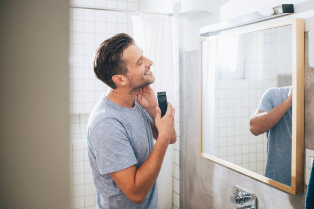 istock Handsome Young Man Shaving His Beard with an Electric Razor 1291413594