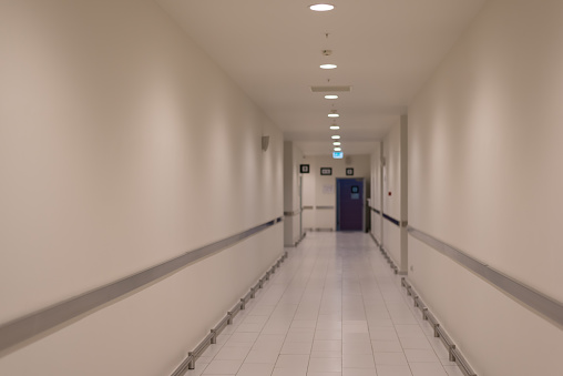 Defocused white service corridor without windows in modern building.