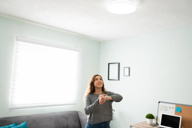 istock Woman using her smartwatch to turn on her smart light bulb 1291414995