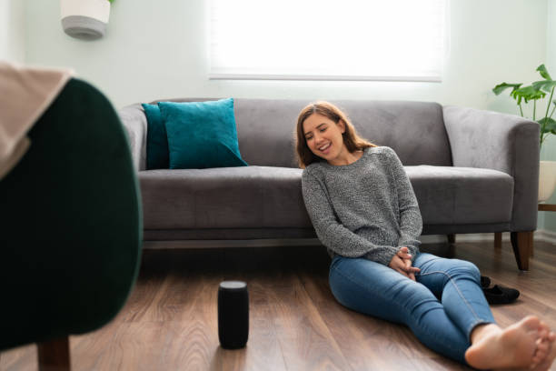 mujer sonriente probando su nuevo altavoz inteligente en casa - attractive female only young women music living room fotografías e imágenes de stock