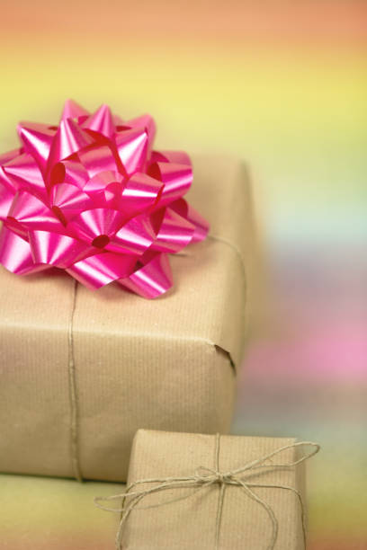 istock Two Gift boxes wrapped in plain brown paper with pink decoration and rainbow background, present for birthday or Valentine's day, mother's day background texture 1291415535