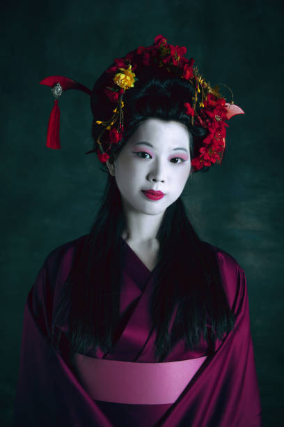 Young japanese woman as geisha on dark green background. Retro style, comparison of eras concept. Inspiration. Young japanese woman as geisha isolated on dark green background. Retro style, comparison of eras concept. Beautiful female model like bright historical character, old-fashioned. modern geisha stock pictures, royalty-free photos & images