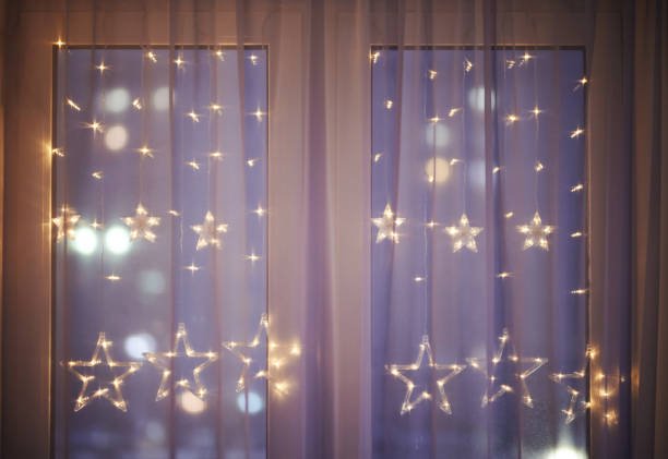 istock Christmas decoration lights under window curtain 1291418491