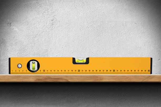 Bubble Level on a Wooden Shelf on White Wall Closeup of an orange bubble level or spirit level on a wooden shelf on white wall. spirit level stock pictures, royalty-free photos & images