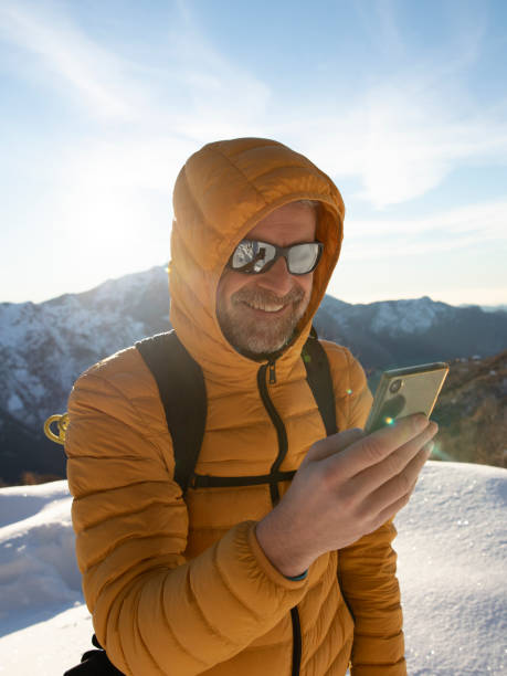 istock Happy man checking smartphone during hiking on snowy mountain 1291422397