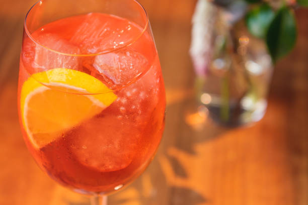 istock Orange cocktail with orange garnish in wine glass, Spritz in sunny setting. 1291422550