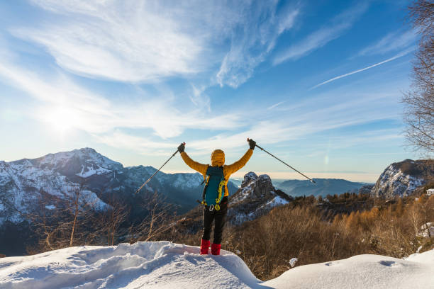 istock Hiker on snowy mountain with hands raised to the clear sky 1291422806