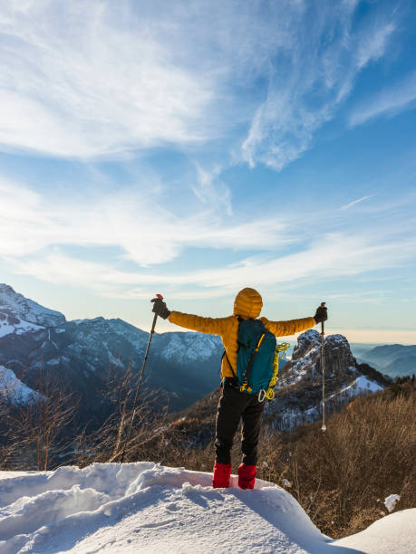 istock Hiker on snowy mountain with hands raised to the clear sky 1291422849