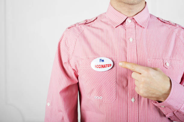 istock Middle age caucasian man in red shirt pointing with his finger at button pin with text I'm vaccinated 1291422918