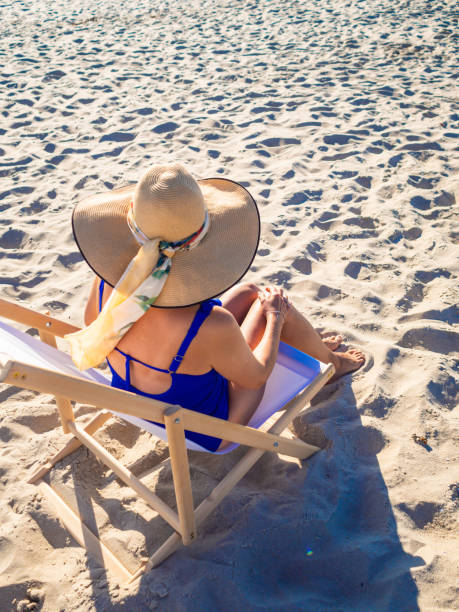istock Woman relaxing on beach sitting on sunbed 1291423115