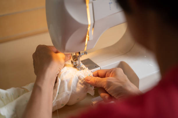 istock asian senior woman using sewing machine making baby clothes at home. 1291423204
