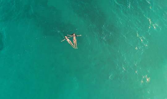 Aerial view of youngs girls in the blue sea in oaxaca mexico from above. Concept of aerial view of young girls in vacations