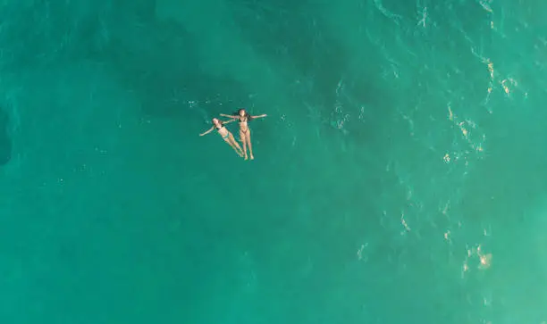 Photo of Aerial view of youngs girls in the blue sea in oaxaca mexico from above. Concept of aerial view of young girls in vacations