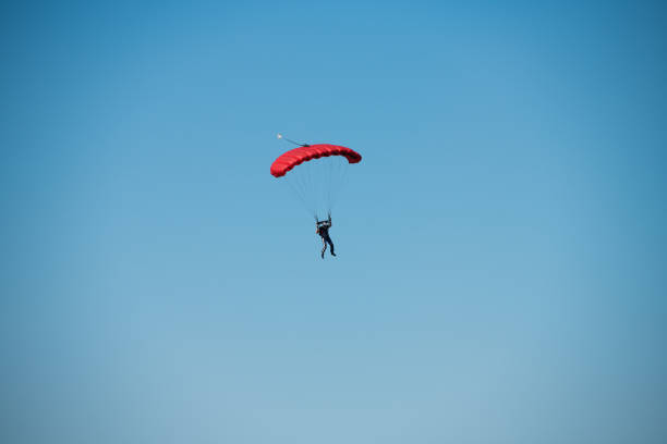istock Parachutist on the background of blue sky 1291428542