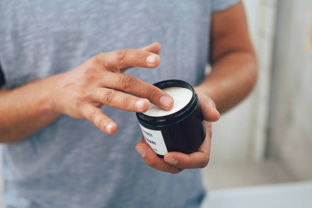 Anonymous Young Man Using an Aftershave Moisturizer After a Morning Shave Close up shot of an anonymous young Caucasian man using an aftershave moisturizer after a morning shave in a bathroom. hand-hygiene-day stock pictures, royalty-free photos & images