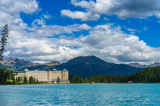 Fairmont Chateau Lake Louise in sunmmer sunny day morning. Blue sky and white clouds reflected on the turquoise color lake water surface. Beautiful landscape in Banff National Park, Alberta, Canada.