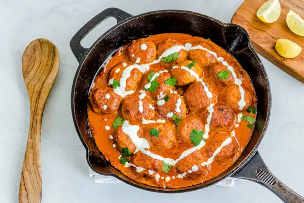Butter Chicken Meatballsin Skillet with Cilantro and Lemon Top Down Photo