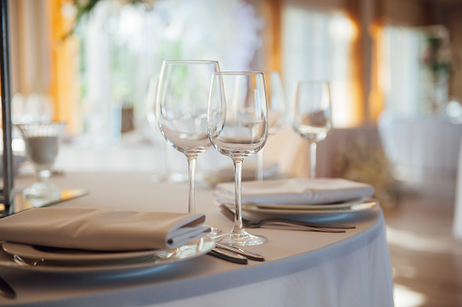 Luxurious restaurant. Luxurious interior, white tables, serving dishes and glasses for guests.