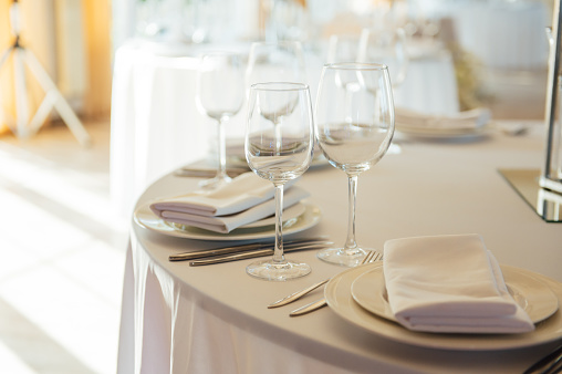 Luxurious restaurant. Luxurious interior, white tables, serving dishes and glasses for guests.