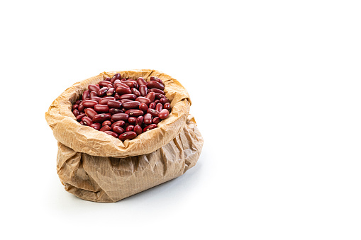 Legume family: Kidney beans in a brown paper bag isolated on white background. High resolution 42Mp studio digital capture taken with SONY A7rII and Zeiss Batis 40mm F2.0 CF lens