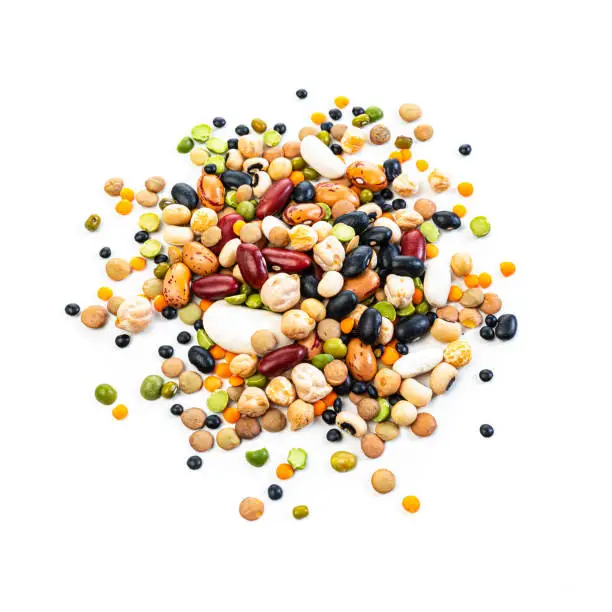 Food Backgrounds: large variety of multicolored dried mixed beans and legumes arranged in a heap isolated on white background. The composition includes green, yellow and brown lentils, chick-peas, black beans, Pinto beans, Kidney beans, fava beans, white beans, mung beans and soy beans among others. High resolution 42Mp studio digital capture taken with SONY A7rII and Zeiss Batis 40mm F2.0 CF lens