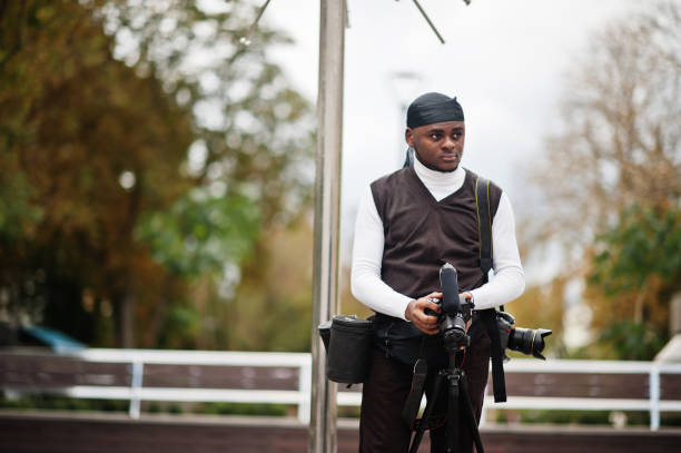 Professional african videographer Young professional african american videographer holding professional camera with pro equipment. Afro cameraman wearing black duraq making a videos. do rag stock pictures, royalty-free photos & images