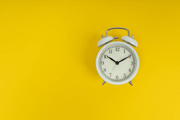 istock Retro alarm clock on yellow background. Old fashioned alarm clock 1291440341